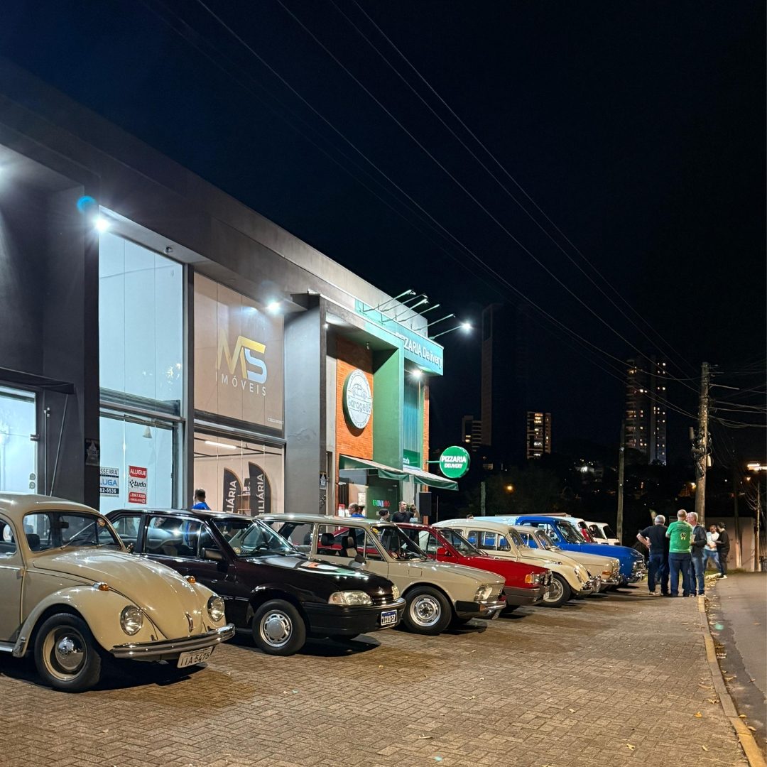 Rua à noite durante o encontro, com o pessoal em volta dos carros