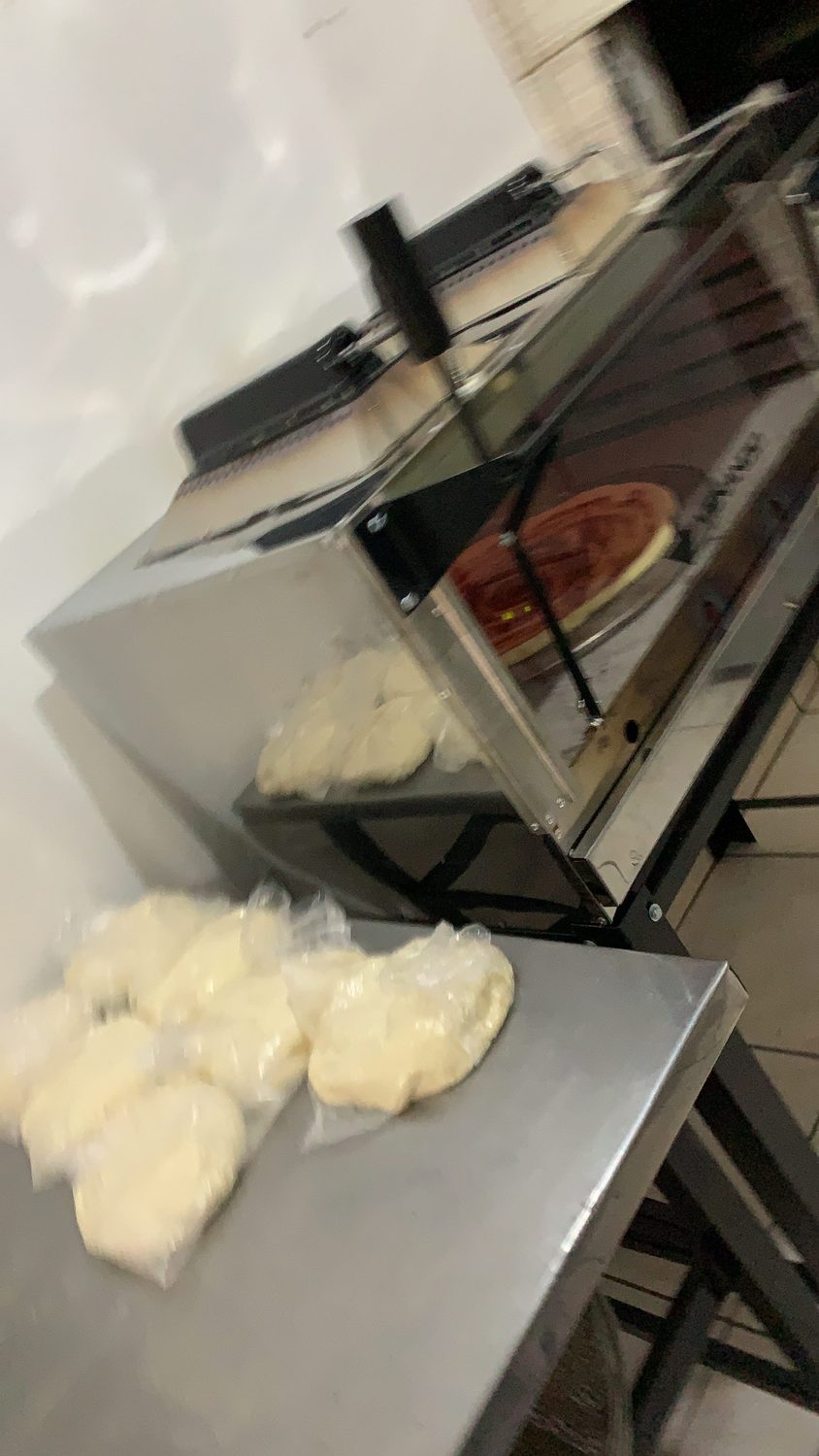 Forno aceso com a pizza e as bolas de massa na frente